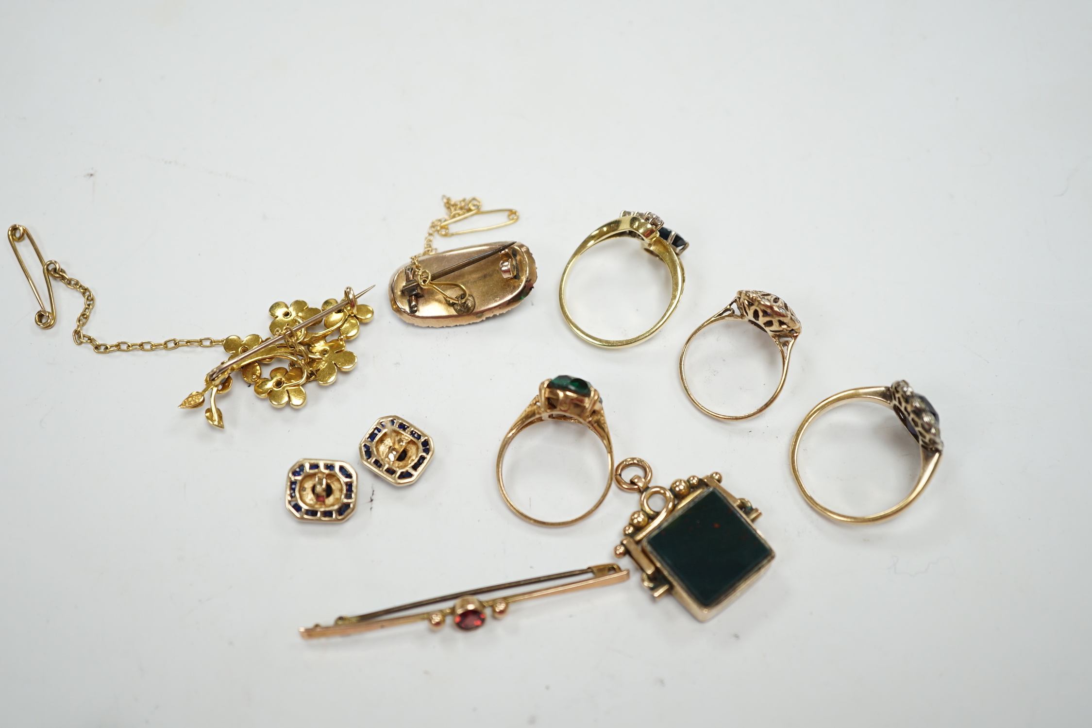 A 750 yellow metal, single stone sapphire and three stone diamond set crossover ring, size, three other yellow metal and gem set rings including a continental 875 white metal and 585 yellow metal, synthetic sapphire or s